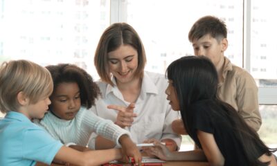 Professora conversando com quatro alunos crianças.